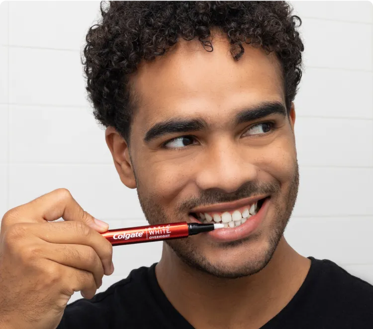 Man applying the Optic White Overnight Teeth Whitening Pen to his bottom front teeth