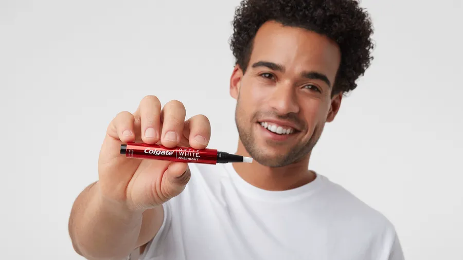 animated GIF showing a man smiling using colgate optic white overnight whitening pen