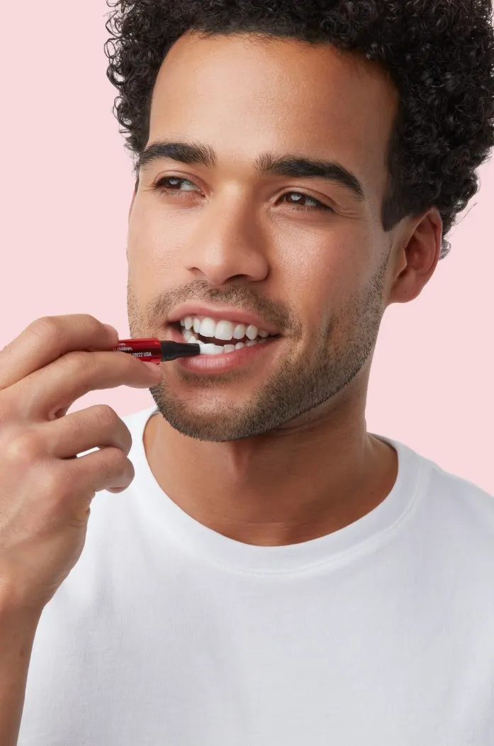 man apply colgate optic white whitening serum on teeth