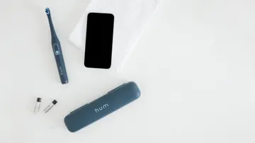 colgate hum adult smart rhythm sonic gray toothbrush, battery, and a smartphone
