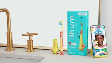 colgate hum smart manual yellow toothbrush for kids and a smartphone holder on the sink counter