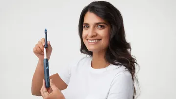 woman showing how to use colgate hum adult smart rhythm sonic gray toothbrush