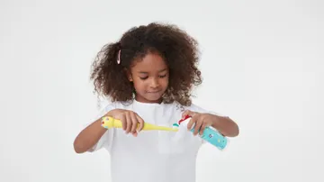 girl showing how to use colgate hum smart battery powered yellow toothbrush for kids