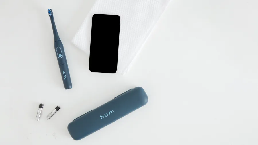 colgate hum adult smart rhythm sonic gray toothbrush, battery, and a smartphone