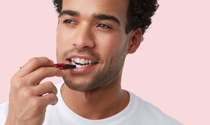 man apply colgate optic white whitening serum on teeth