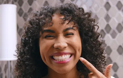 Woman showing her whiten teeth after using optic white comfortfit LED teeth whitening kit